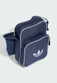 Borsa rettangolare blu navy con doppia zip, caratterizzata da piping azzurro e logo bianco Adidas. Cinghia regolabile per una maggiore comodità nel trasporto.