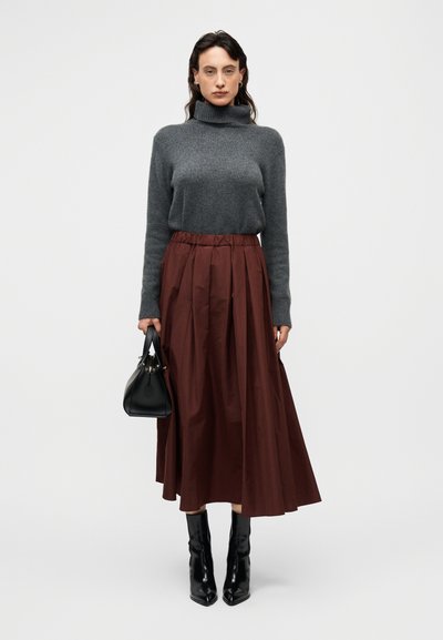 Γκρι πλεκτός πουλόβερ με λαιμόκοψη, καφέ μίντι φούστα με πτυχώσεις, μαύρες μπότες με τακούνι και μια μικρή μαύρη τσάντα. Απλός και κομψός σχεδιασμός.