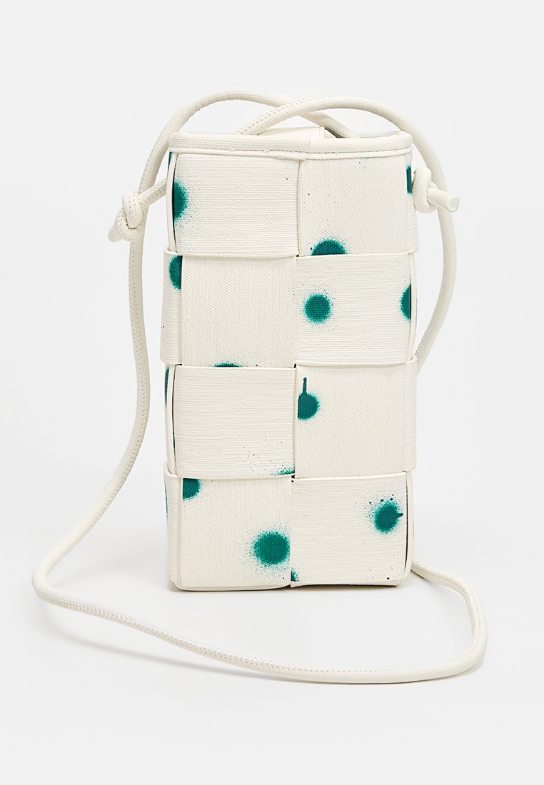 Kleine witte geweven stoffen crossbody tas met verstelbare schouderband en teal verfspetters op de geweven panelen.