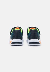 Scarpe da ginnastica nere con tomaia in rete, accenti verde neon, interno arancione e suole bianche. Presentano una fascetta regolabile per la chiusura.