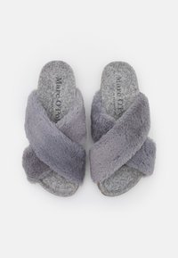 Chaussons à brides croisées en fausse fourrure grise avec une texture douce et des semelles intérieures en feutre gris. La semelle présente une finition lisse et un design minimaliste.