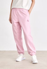 Roze joggingbroek met een elastische tailleband, manchetten bij de enkels en een klein geborduurd logo. Gemaakt van zachte stof, ontworpen voor comfort.