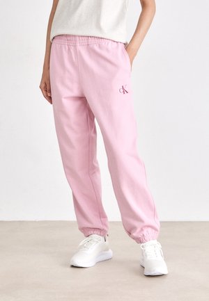 Rosa joggebukser med elastisk midje, stramme ankler og en liten brodert logo. Laget av mykterende stoff, designet for komfort.
