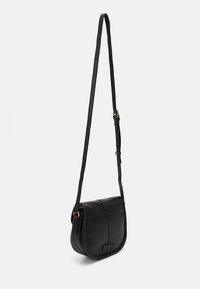 Czarna skórzana torba na ramię o zaokrąglonym kształcie, cienkim pasku i mosiężnych akcentach. Charakteryzuje się przeszytym wzorem oraz małym logo z przodu.