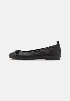 Ballerines noires matelassées avec un bout rond, ornées d'un petit nœud et d'un accent en perles. Matière lisse avec une semelle basse et plate.