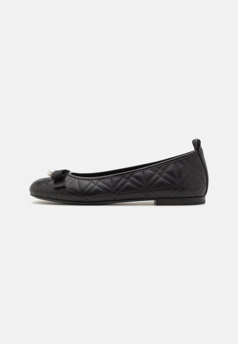 Ballerines noires matelassées avec un bout rond, ornées d'un petit nœud et d'un accent en perles. Matière lisse avec une semelle basse et plate.