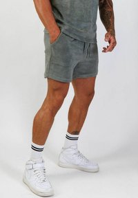 Grå bomullsblandade shorts med sidofickor, elastisk midja och dragsko, tillsammans med vita högskurna sneakers och randiga strumpor.