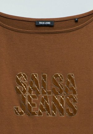 Chemise marron avec un col rond et le texte décoratif "SALSA JEANS" en design clouté et à motifs sur le devant, étiquette taille petite à l'intérieur du col.