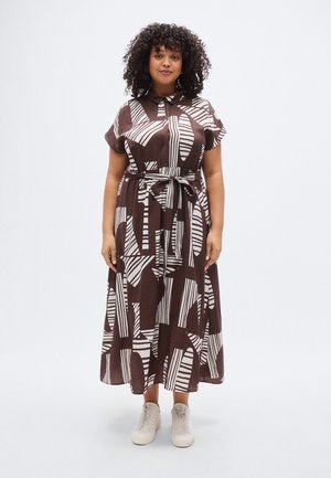 Brun mønstret kjole med hvide abstrakte striber, en krave, korte ærmer og bundet talje, kombineret med lyse sneakers.