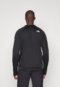 Čierna mikina s dlhým rukávom a okrúhlym výstrihom, s rebrovanými manžetami. Obsahuje biele logo "The North Face" na hornej časti chrbta.