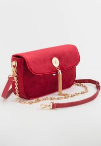 Czerwona welur torba na ramię z łańcuszkiem w złotym odcieniu i detalami frędzlami, z zaokrągloną klapą i gładką fakturą. W zestawie regulowany pasek.