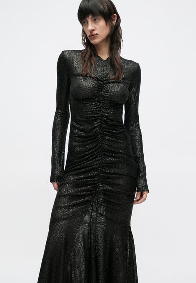 Rochie neagră cu mâneci lungi din material texturat, cu detalii strânse pe partea din față și tiv evazat. Aspect neted și strălucitor.