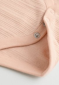 Tessuto a coste di colore rosa chiaro con una consistenza morbida. Presenta bottoni a pressione lungo il bordo e una finitura liscia al colletto e ai polsini.