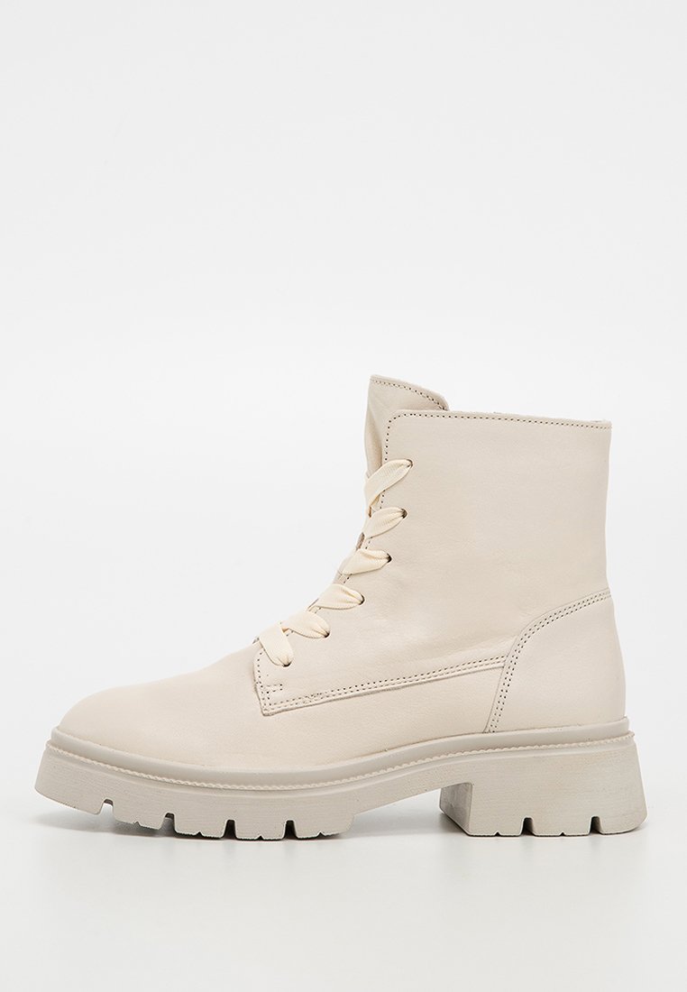 Bottine en cuir beige avec un bout rond, un laçage à l'avant, une semelle épaisse et des détails de couture subtils. Finition lisse avec une texture mate.