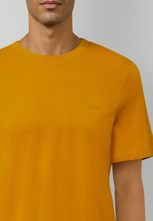 Senfgelbes T-Shirt mit kurzen Ärmeln, rundem Ausschnitt und einem kleinen geprägten Logo auf der Brust. Glatte Stofftextur.