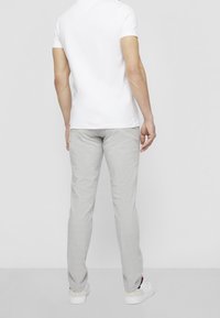 Light gray, tailored pants with a smooth texture and subtle pattern, paired with a plain white t-shirt and white sneakers.
