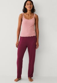 Light pink tank top with lace trim paired with dark maroon, loose-fitting pants. Both items have a smooth texture and casual design.