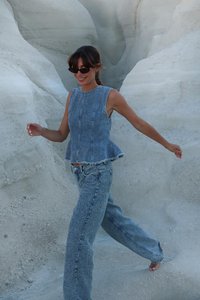 Denimoutfit med en ärmlös peplumtop och raka jeans i ljusblått med texturerad yta och fransade kanter.