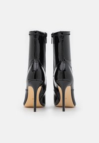 Czarne skórzane botki za kostkę o eleganckim fasonie, wysokich szpilkach i z suwakiem z tyłu. Gładka, błyszcząca faktura.