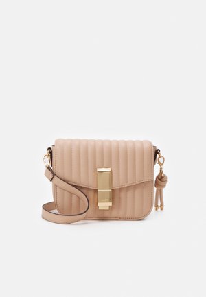 Beige quilted crossbody bag with vertical stitching, gold rectangular clasp, detachable strap, and knotted tassel charm on side.