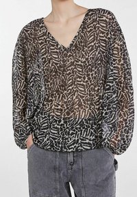 Blusa nera trasparente con scollatura a V, caratterizzata da un motivo astratto bianco e beige, maniche lunghe a palloncino e orlo arricciato.