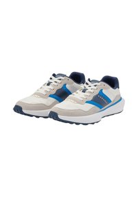 Beige ja tumesiniste sneakersite paar, valgete paeltega, siniste aktsentidega ja paksude valgete talladega, nurga all, et näidata esipoolt ja külgpilu.