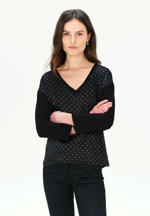 Top nero a V con maniche lunghe di colore nero solido e motivo a pois blu chiaro sul corpo. Tessuto morbido con una vestibilità comoda.