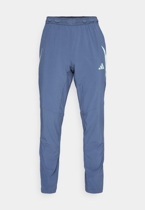 Dunkelblaue Sporthose aus leichtem Material mit elastischem Bund, schmal zulaufendem Bein und einem weißen Markenlogo an der Seite.