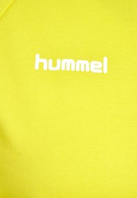 Bright yellow T-shirt with a ribbed texture and white "hummel" logo on the front. Short sleeves and round neckline.