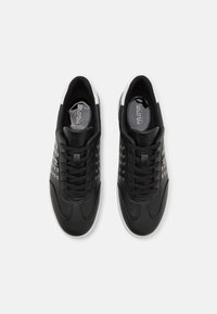 Baskets en cuir noir avec une finition lisse, dotées d'accents en œillets argentés et de lacets noirs. Semelles blanches et logo sur les semelles intérieures.