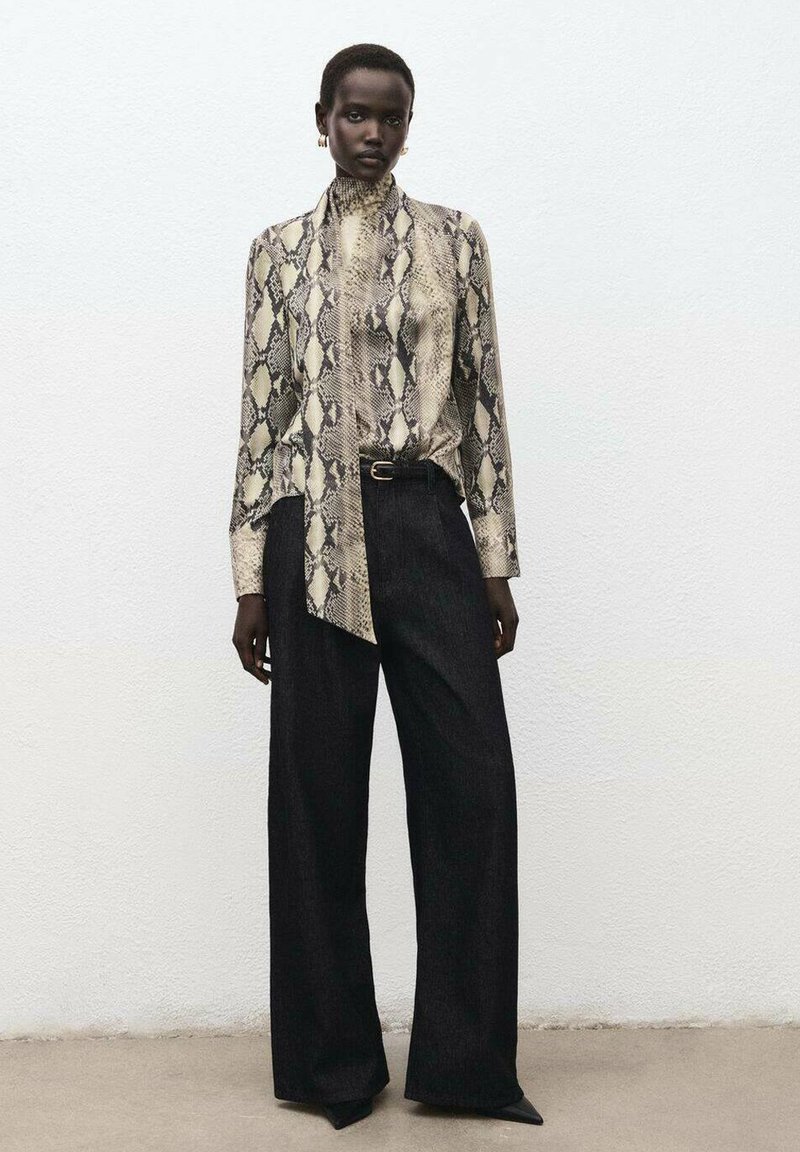 Long-sleeve blouse with a beige and black snake pattern, paired with wide-leg black pants. Material appears smooth; blouse features a high collar.