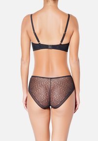 Ensemble de lingerie noire comprenant un soutien-gorge en dentelle avec bretelles réglables et une culotte transparente assortie ornée de motifs en zigzag et points. Texture douce.
