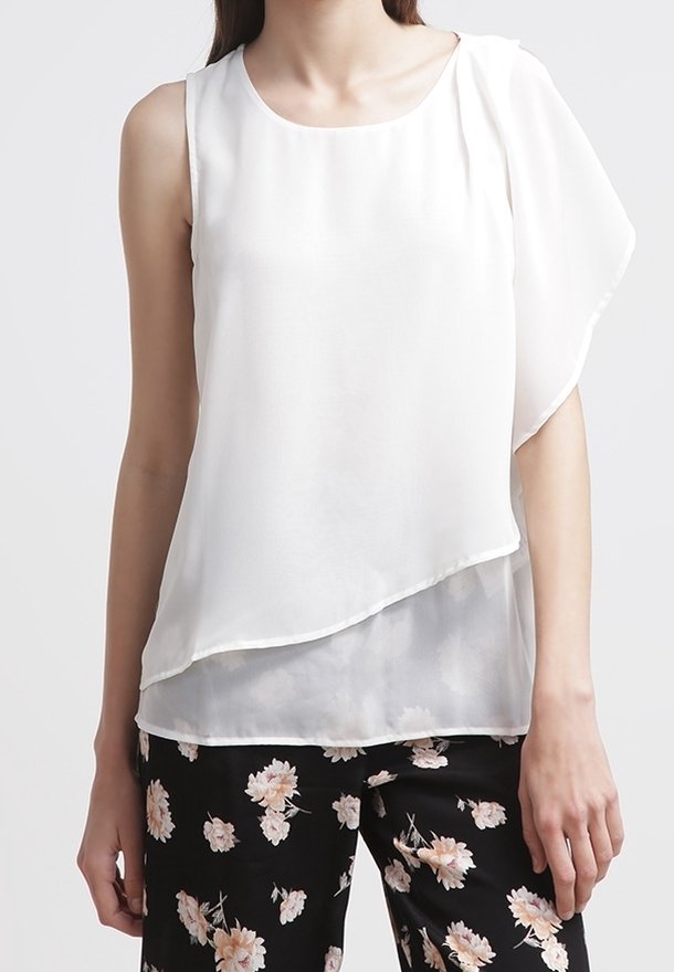 Blouse blanche asymétrique sans manches avec détail drapé à l'épaule, associée à un pantalon noir à imprimé floral rose clair.