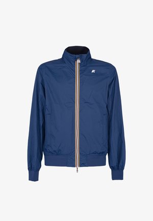 Chaqueta ligera azul para hombre con cremallera, cuello alto, puños elásticos, dobladillo acanalado y pequeño logo blanco en el pecho.