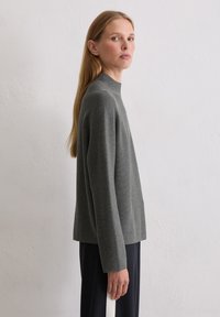 Grauer, langärmeliger Pullover mit hohem Kragen. Aus weichem, strukturiertem Stoff gefertigt, mit lässigem Schnitt und gerader Silhouette.