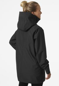Czarna wodoodporna kurtka z kapturem, o prostym kroju, długich rękawach i gładkiej strukturze. Minimalistyczny design bez widocznych logotypów.