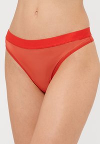 Rdeče mrežaste bikinke z voljnim rdečim elastičnim pasom, ki se ponašajo z nizkim rezom in gladko teksturo za udobje.