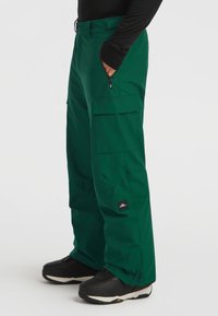 Green snow pants with a slight shine, featuring cargo pockets, a zipper on the side, and a branded label on the thigh. Textured fabric, straight fit.