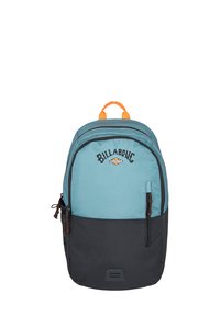 Mochila con una sección superior en color verde azulado y una sección inferior negra, que cuenta con un asa superior naranja, bolsillos con cremallera y un logo en la parte frontal.