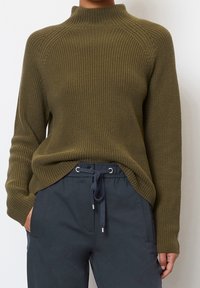 Olivgrüner, gerippter Strickpullover mit hohem Kragen, der Raglanärmel und einen leicht längeren hinteren Saum hat.