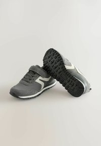 Gray athletic shoes with a Velcro strap, featuring suede and mesh materials, black rubber sole with a textured tread, and white accents.