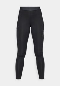 Leggings de sport noirs au design ajusté, fabriqués en tissu extensible. Présentent des poches latérales et un logo "TERREX" blanc.