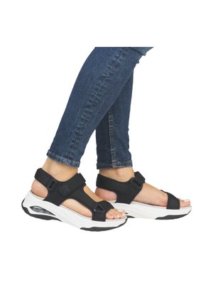 Black sporty sandals featuring adjustable straps, a molded footbed, and a thick white sole with a textured black outsole.