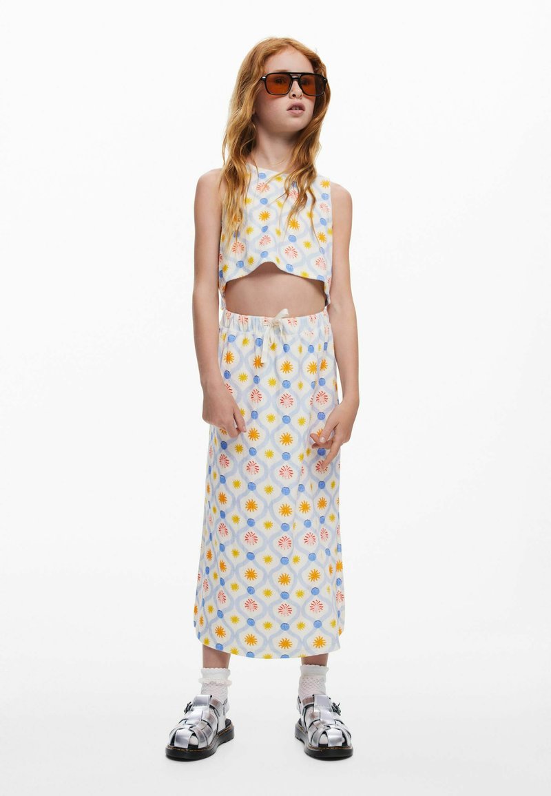 Dvojdielny outfit pozostávajúci z krátkeho topu a zodpovedajúcej dlhej sukne. Kvetinový vzor v pastelových farbách, vyrobený z ľahkej látky. Strieborné sandále.