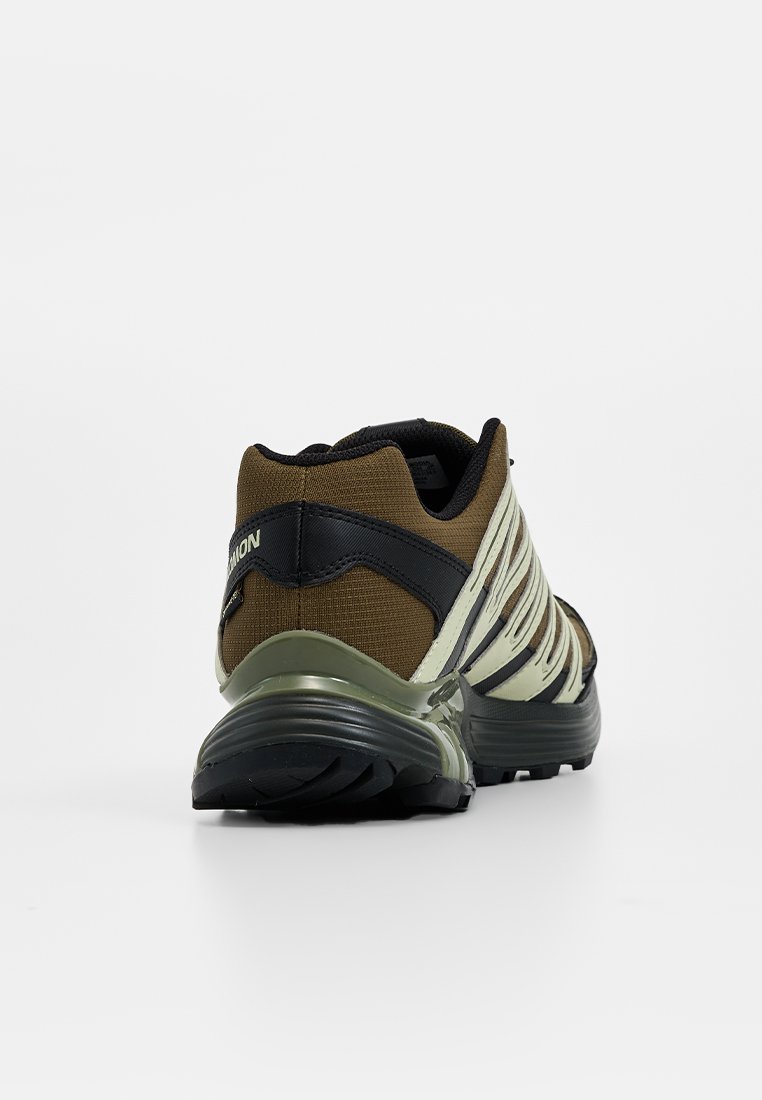 Brązowy i czarny but sportowy z teksturowanym materiałem górnym oraz amortyzowaną podeszwą, z odblaskowym akcentem i smukłym designem.