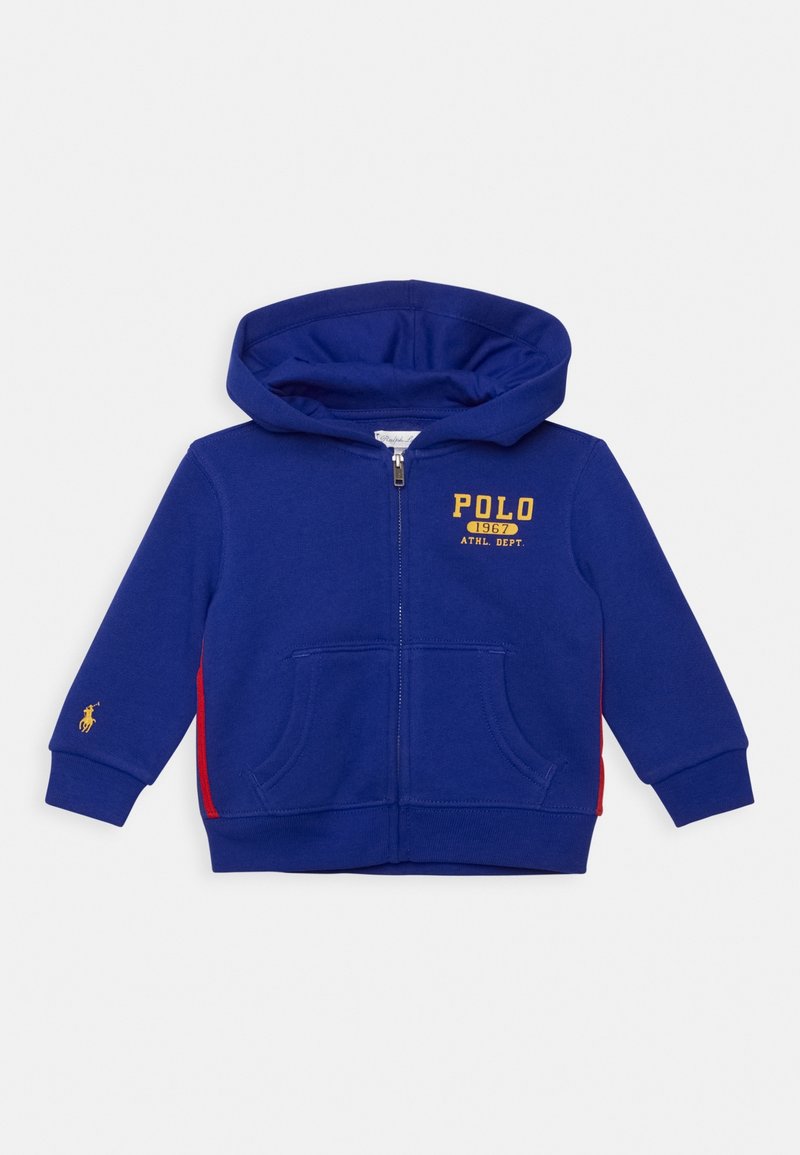 Sudadera con capucha para niños, color azul, con cremallera, capucha, bolsillos delanteros, rayas laterales rojas, texto amarillo "POLO 1967 ATHL. DEPT." y pequeño logo de caballo en la manga izquierda.
