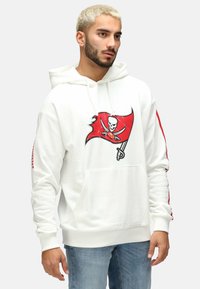 Weißer Hoodie mit einem roten Piratenflaggen-Graphic, das ein Totenkopf- und Knochenmotiv zeigt. Rote Streifen entlang der Ärmel. Vordertasche im Känguru-Stil.