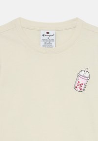 Bežinis marškinėliai su apvaliuoju kaklu, kairėje krūtinės pusėje turintys spalvingą, piešinio stiliaus gėrimo puodelio grafiką. Pagaminti iš medvilnės, su lygiu paviršiumi.