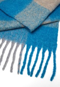 Wollen sjaal met afwisselende tinten blauw en beige, een zachte, textuurachtige afwerking en franjes in blauw en grijs.