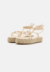 Beiga espadrillosandaler med vävd rep-sula, som har flera remmar och snörningar, slät fotbädd och rund tågdesign.